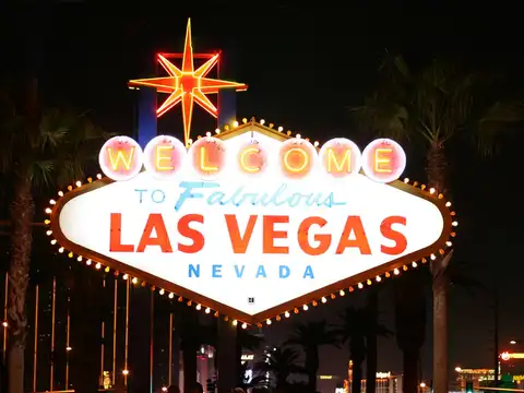 The Welcome to Fabulous Las Vegas Nevada neon sign lit at night, framed by palm trees against a dark sky.